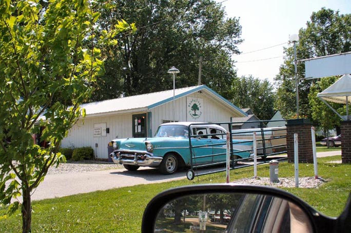 Entrance of Shady Oaks Campground with white and blue classic car